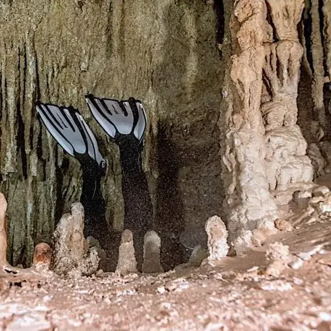 advanced sidemount diver through a cave restriction in Mexico